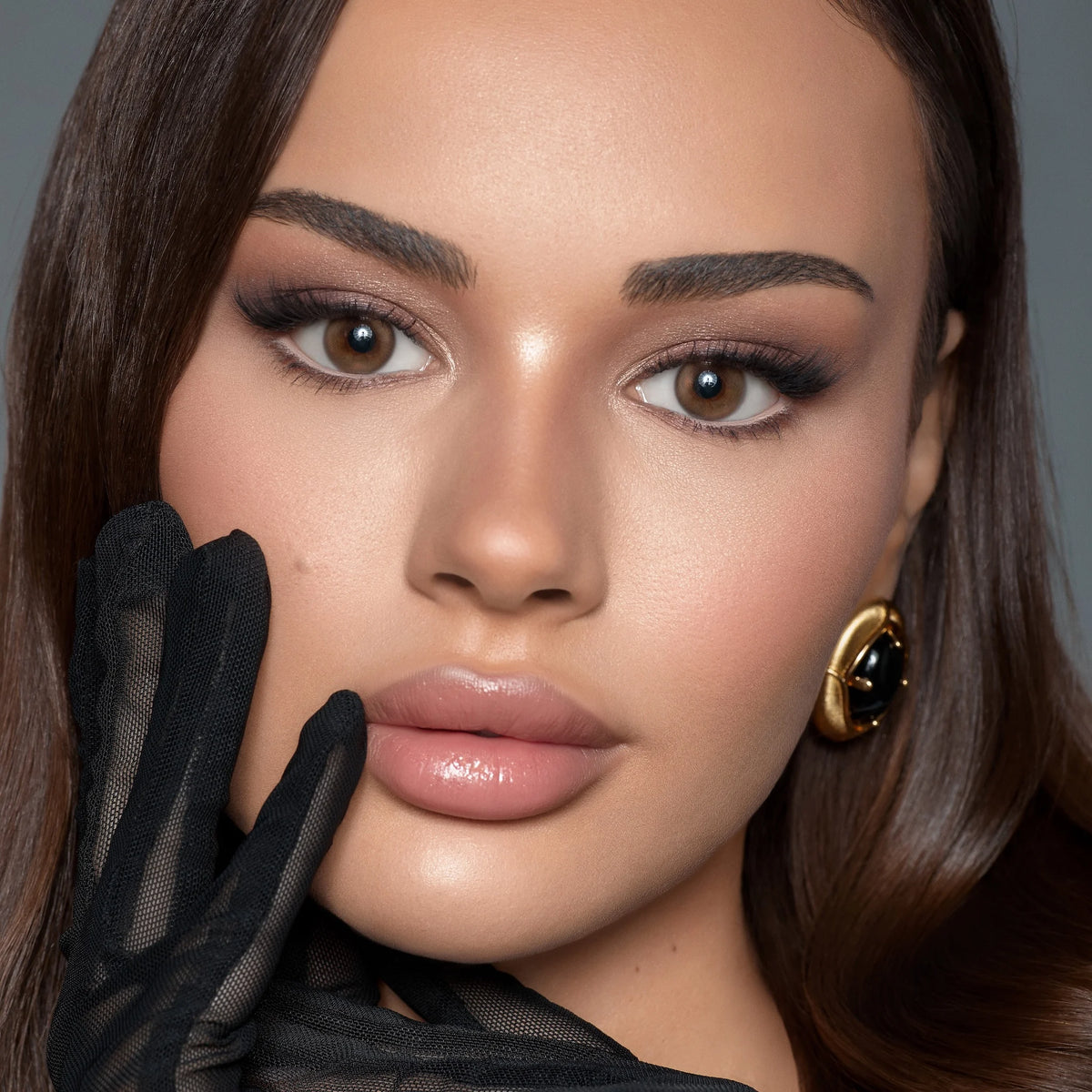 Close-up of a woman with makeup and a black glove, wearing Bella contact lenses named siren bronze